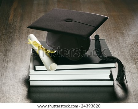 A metaphorical graduation background with a view of a academic hat, diploma and a stack of books on a wooden surface.