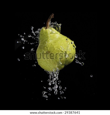A high-speed shot of a pear with splashing water, isolated on a black background.