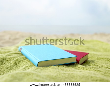 Two books lying on a towel at the beach.