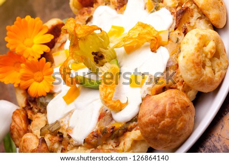Traditional French Cuisine - Gougere cake with vegetables decorated with zucchini flower and small choux.