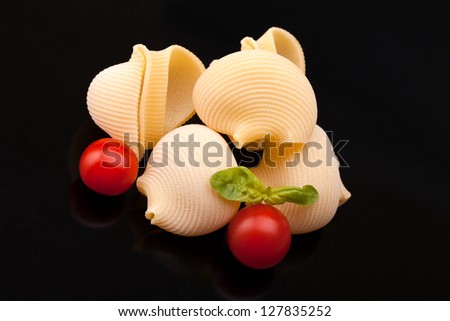 Lumaconi And Cherry Tomatoes - Pasta Varieties - Lumaconi with cherry tomatoes and basil over black background.