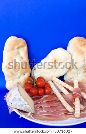 Food & Drinks - Italian Appetizers. Ham (prosciutto crudo), Lagrein wine infused cheese, breadsticks, bread and cherry tomatoes. Vertical pose.