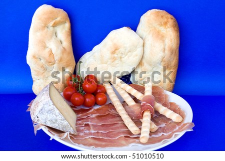 Food & Drinks - Italian Appetizers. Ham (prosciutto crudo), Lagrein wine infused cheese, bread-sticks, bread and cherry tomatoes. Horizontal pose.