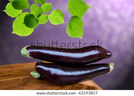 Vegetables - Still life with eggplants on wood table on purple background.