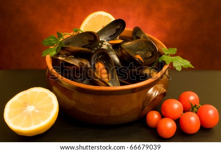 Italian Cuisine - Mussels soup decorated with lemon, parsley and tomatoes.