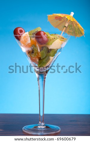 Food - Desserts - Cup with fruit salad decorated with paper umbrella, on blue background.