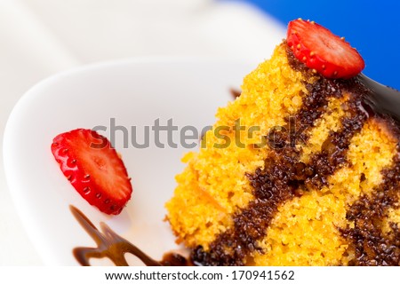 Piece of carrot cake decorated with chocolate and strawberry slices.