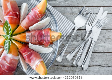 Closeup overhead view of half plate with melon slices wrapped in prosciutto and mozzarella slices.