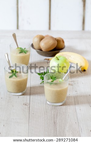 Glasses with iced sorbet made with green apples, kiwi and banana, decorated with fresh mint leaves.