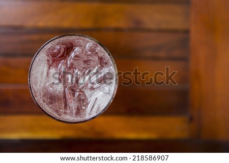 glass of iced raspberry soda on table from top view