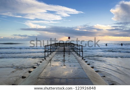 Surfers enjoy the waves off a small jetty on Boscombe beach near Bournemouth in Dorset.