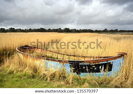 Rusty old shipwrecked and bandoned boat in reeds on salt marshes in Poole Harbour, Dorset.