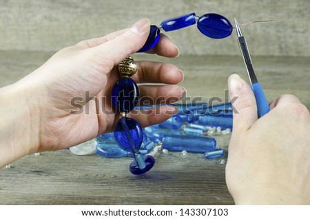 Woman\'s hands making a necklace from glass beads