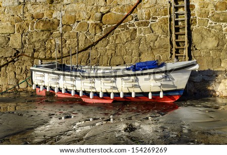 White boat lined with small buoys and floats against the harbour wall at St Michael\'s Mount in Cornwall