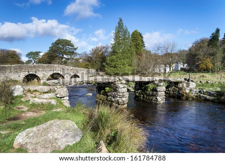 An ancient clapper bridge and arched bridge crossing the East Dart river at Post Bridge on Dartmoor