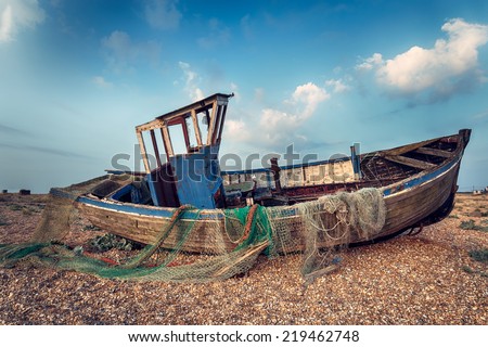 Old wooden fishing boat washed up on a shingle beach