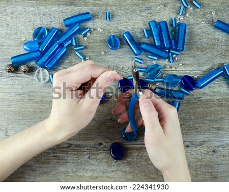 Woman\'s hands making working with glass beads