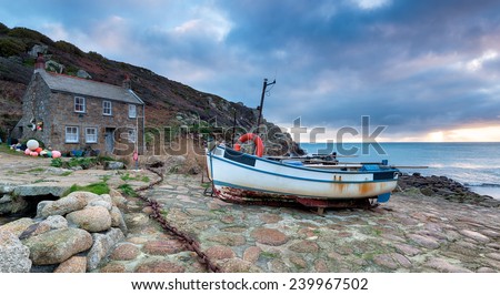 The South West Coast Path as it passes through fishing boats and cottages at Penberth Cove near Penzance in Cornwall