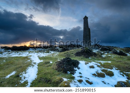 Storm clouds gather over an abandoned chimney stack left over from copper mining at Darite on Bodmin Moor in Cornwall