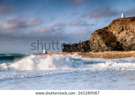 Waves and surf at Portreath harbour on the coast of Cornwall, the structure on the pier is known as the Monkey Hut and the one on the cliffs the Pepperpot