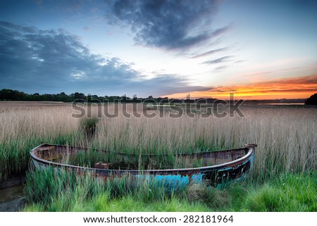 Sunrise over an old fishing boat washed up in reeds at Poole Harbour on the Dorset coast