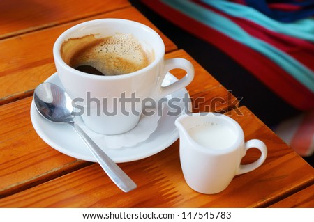 White coffee and milk cups on a wooden cafe table