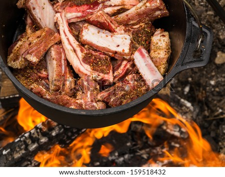 Cauldron full of lamb meat - cooking on fire