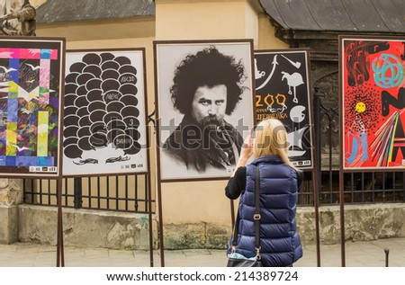 LVIV, UKRAINE - MAY 17: young woman using her smartphone to take a photo of posters dedicated to Taras Shevchenko\'s 200-year anniversary exposed on Halytska street on May 17, 2014 in Lviv, Ukraine.