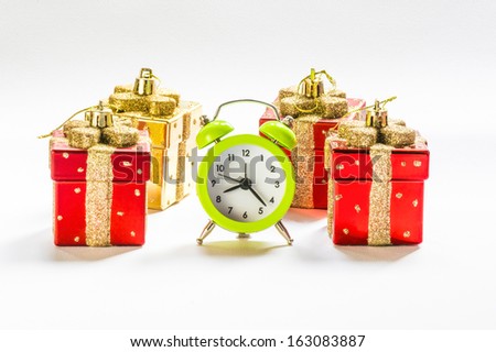 Christmas time: Green alarm clock between present shaped Christmas decorations