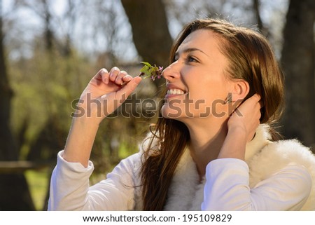 Young woman playing with her hair, smelling mint flower, smiling