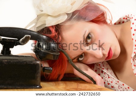 Waiting for you\'re call! Sad redhead woman with a retro look waiting for the phone to ring looking at the camera, isolated on white