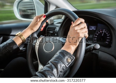 Woman\'s hands on the steering wheel of the car.