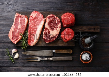 Variety of Raw Black Angus Prime meat steaks Blade on bone, Striploin, Rib eye, Tenderloin fillet mignon on wooden board