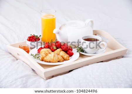 Breakfast in bed with tea and croissants on a tray