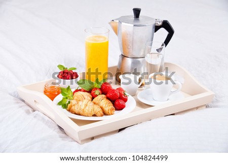 Breakfast in bed with coffee and croissants on a tray