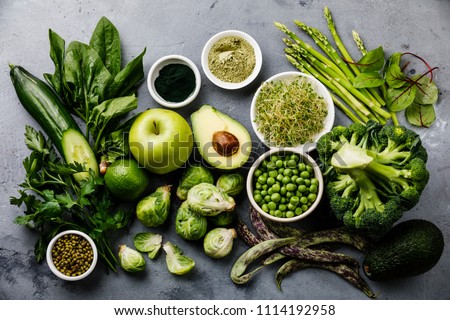 Healthy Green food Clean eating selection Protein source for vegetarians: avocado, asparagus, apple, broccoli, spinach, spirulina, green peas on gray concrete background