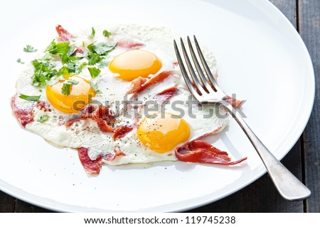 Traditional breakfast with eggs and bacon on white plate