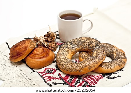 cup of black tea with a cinnamon rolled buns and doughnut-shaped bread rolls