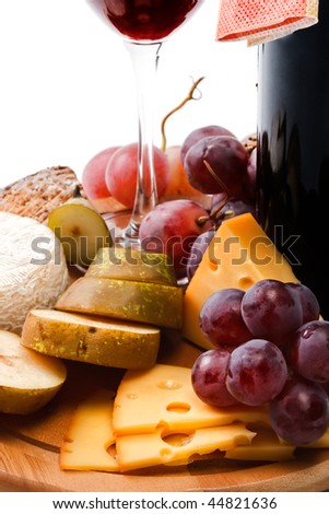 Red wine and assortment of cheese and fruits close-up on white background