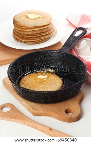 Pancakes on plate and pancake in pan on white background