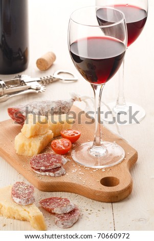 Tow wineglass with red wine and assortment of cheese and fruits on white background