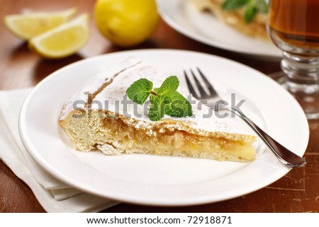 Slice of lemon pie with lemons on background