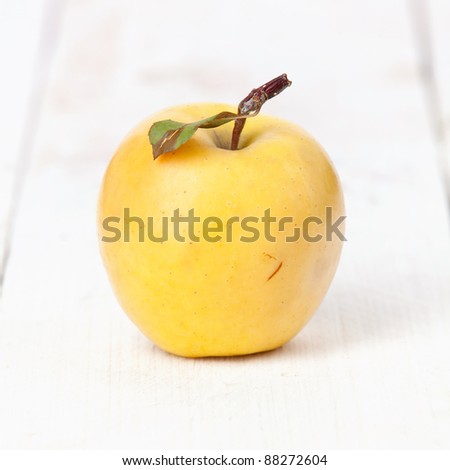 Fresh yellow apple on white wooden background