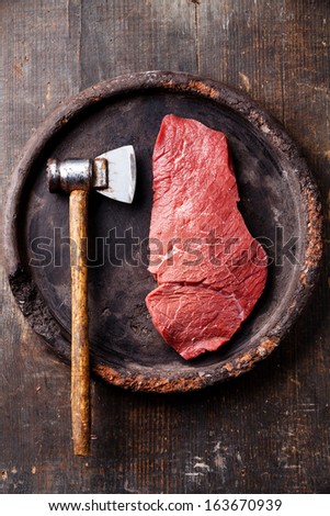 Raw fresh meat and meat cleaver on dark background
