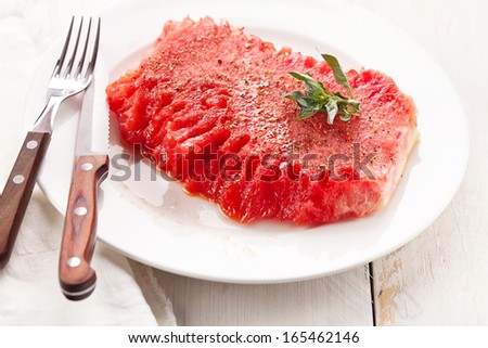 Watermelon slice with fork and steak knife on white plate