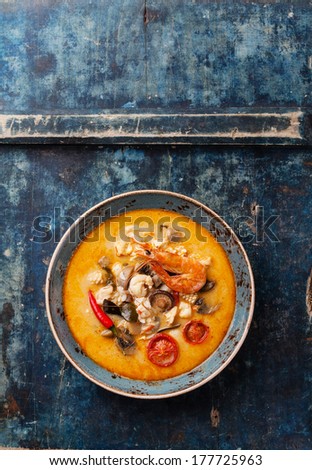 Spicy Thai soup Tom Yam with Coconut milk, Chili pepper and Seafood on blue background