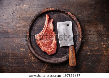 Raw fresh meat Ribeye Steak and meat cleaver on dark background