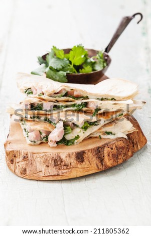 Quesadilla with cheese, meat and vegetables on olive wood cutting board