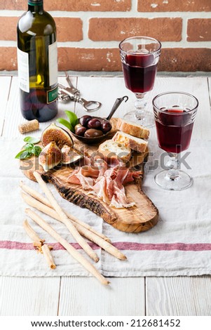 Prosciutto ham, Olives and red Wine on olive wood cutting board