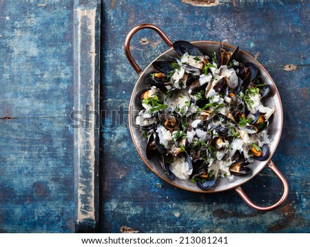 Mussels and Dor Blue sauce in copper cooking dish on blue background